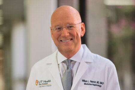 Dr. Henrich smiling in a white coat