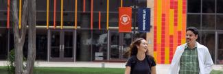 Academic learning center with two medical students walking and laughing by UT Health San Antonio and UT San Antonio signage