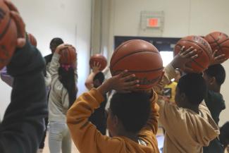 Spurs PE Takeover photo of children holding basketballs on their head at UT Health San Antonio event